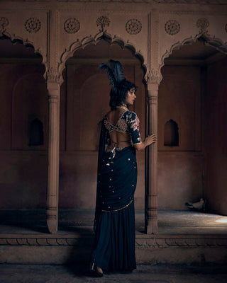 Model is posing to show the back of the blouse and the pre-draped saree 