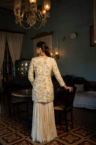 Paulmi and Harsh model posing to show the back of the Indian kurta with sharara in white.