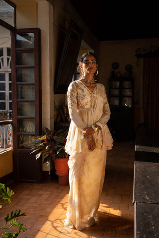 Featuring an ivory printed pre–stitched crepe saree peplum set with antique gold dori and embellished hand work. Designed by Paulmi and Harsh.