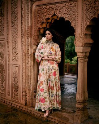 A floral jaal print kaftan set in Paulmi and Harsh signature ivory chintz floral print, featuring a pair of birds in their enchanting habitat. It has a V neck, hand-embroidered patch border, drop sleeves, front slit and elastic gathers to accentuate the waist. The border is hand-embroidered in zardozi. It is paired with straight cut printed pencil pants.