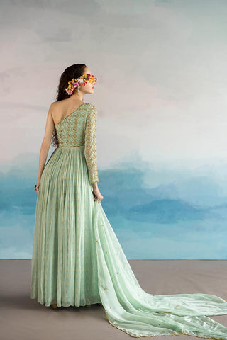 The model posing to show the back of the light mint one shoulder dress.