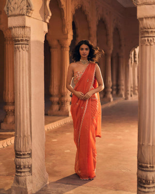 A delicate organza pre-draped saree, with hand-embroidered all-over buttis and scallops. It is paired with a corset blouse with hand-embroidered&nbsp;chintz motifs and a criss-cross tie up on the back.