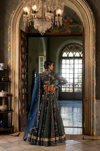 Model showcasing the back look of the lehenga set in paulmi and harsh floral print heavily highlighted using antique jewel tones.