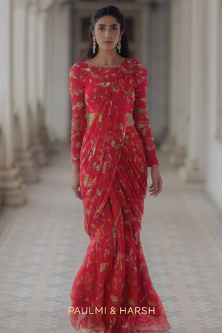 A floral printed pre–stitched saree in the shade of peony pink, a great option for a roka ceremony. Designed by Paulmi and Harsh.