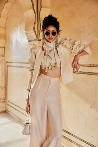 An ivory jacket set crafted from luxurious silk organza fabric. It features a blouse and jacket, embroidered in floral jaal cutwork with volume detailing, and trousers. The silk scarf has scallops and beautiful tassel detailing.