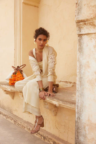 Ivory Luxurious Silk Crop top and Long Jacket Set designed by Paulmi and Harsh. It has an eye catchy cutwork technique details. A perfect look for a beach wear, party, summer wear, dinner date, a dress to flaunt and style, an every day wear.