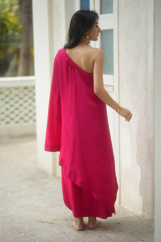 The back look of the A rani pink one shoulder top and drape skirt. The skirt has a bow detailing on the side. An extremely easy to wear ensemble designed by Paulmi and Harsh