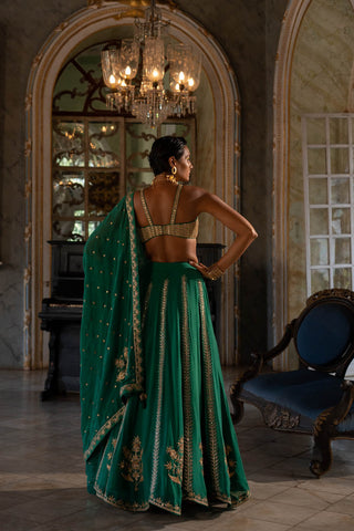 Model posing to show the back of the one strap blouse and lehenga with dupatta.