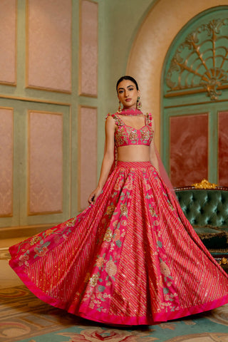 A blooming pink floral printed lehenga set with hand embroidered details, beautifully adorned using tassels, it is paired with hand–highlighted blouse and net dupatta. Designed by Paulmi and Harsh