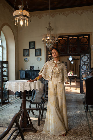 Indo Western Ivory Soothing Floral Print Jumpsuit paired with an embroidered jaal cape jacket with antique sequins, tone and embellished with gold detailing, designed by Paulmi and Harsh. A perfect women clothing wear for day out, party, summer wear, dinner date, a dress to flaunt and style.