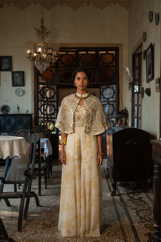 Indo Western Ivory Soothing Floral Print Jumpsuit paired with an embroidered jaal cape jacket with antique sequins, tone and embellished with gold detailing, designed by Paulmi and Harsh. A perfect women clothing wear for day out, party, summer wear, dinner date, a dress to flaunt and style.