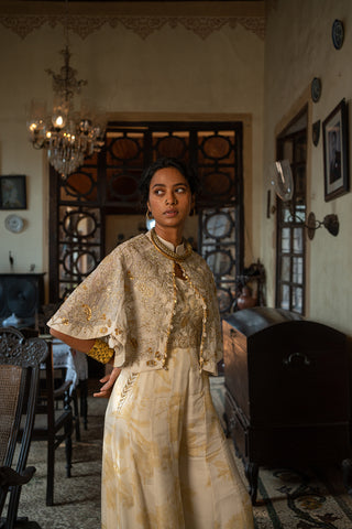 Indo Western Ivory Soothing Floral Print Jumpsuit paired with an embroidered jaal cape jacket with antique sequins, tone and embellished with gold detailing, designed by Paulmi and Harsh. A perfect women clothing wear for day out, party, summer wear, dinner date, a dress to flaunt and style.