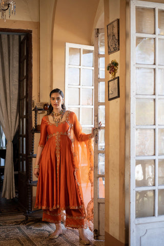 Featuring a rust chiniya silk anarkali set paired with tissue base dupatta with antique gold zari resham embroidery. Designed by Paulmi and Harsh.